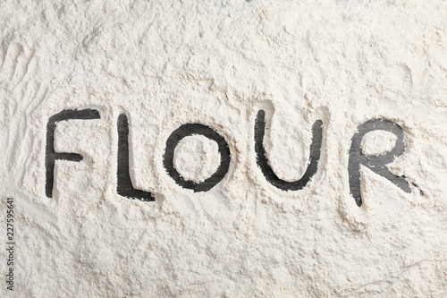 Word written on layer of flour, top view