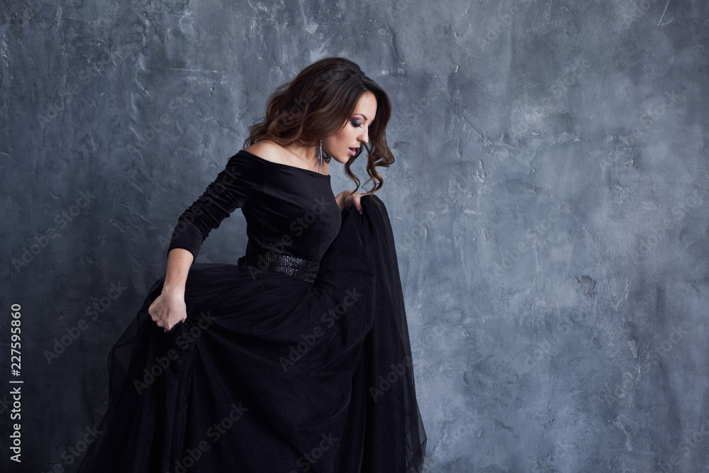 Beautiful girl with makeup and hairdo in a black dress