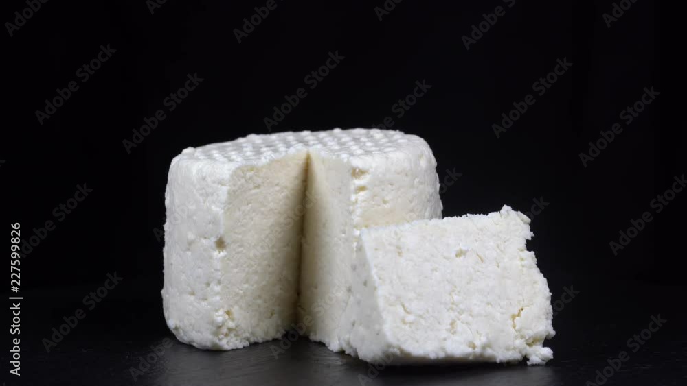 Rotation brynza cheese on black slate plate. Delicious piece of white brynza cheese on black background, close up, macro Rotation brynza cheese on black slate plate. Delicious piece of white brynza cheese on black background, close up, macro
