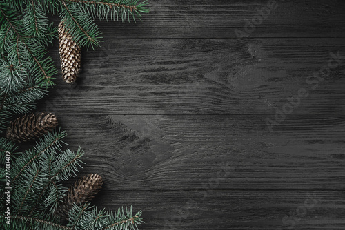 Christmas card. Black wood background with branches and fir cones in the side, top view photo