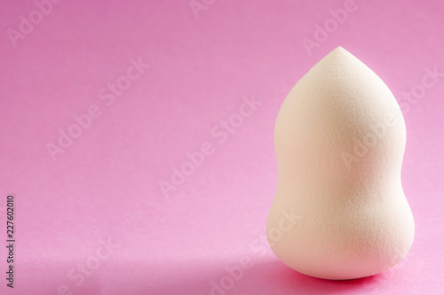 Face foundation application tool and makeup products concept with a beauty blender sponge isolated on a pink background and copy space photo