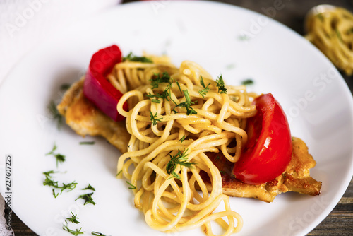 pasta and fried meat with spices and vegetables on a wooden board