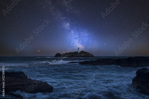 Vibrant Milky Way composite image over landscape of Godrevy Lighthouse in Corwnall England