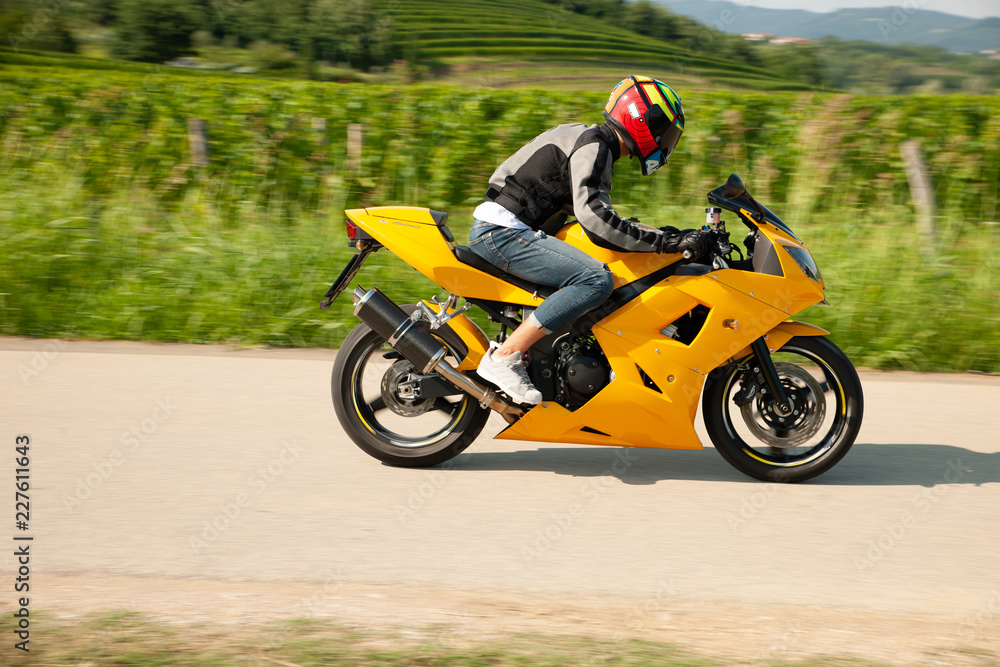 Man drive a motorbike on a country road with vineyards in background