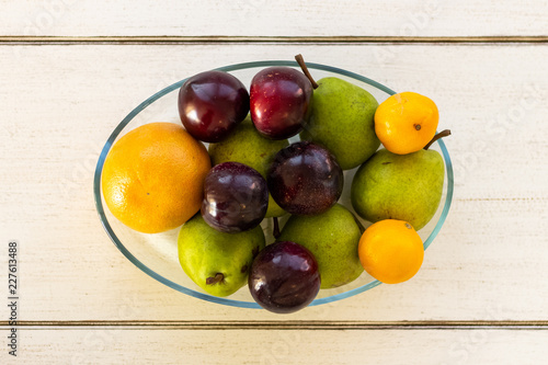 Fresh fruit in a bowl lying on a wooden table from a top view