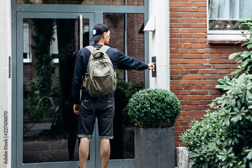 Slika na platnu The tourist rings the doorbell to check in to the room he has booked or the student with the backpack returns home after classes at the institute or on vacation