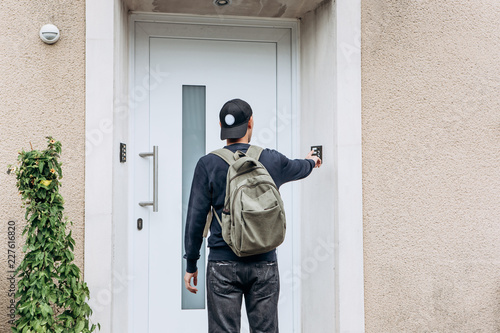 Obraz na płótnie The tourist rings the doorbell to check in to the room he has booked or the student with the backpack returns home after classes at the institute or on vacation. w salonie