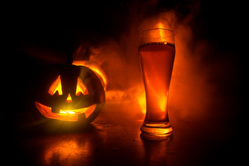 Glass of cold light beer with pumpkin on a wood background for Halloween. Glass of fresh beer and pumpkin on a dark toned foggy background