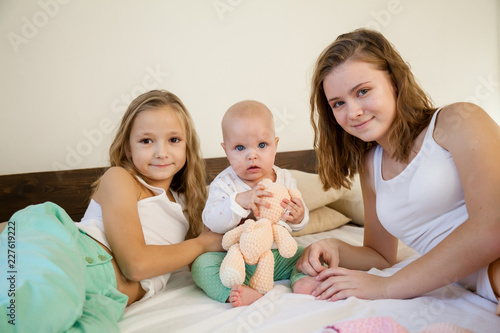 three girls play sisters in the bedroom on the bed in the morning photo