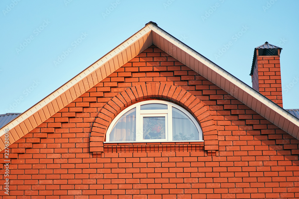 A small window under the roof in a brick cottage A small window under the roof in a brick cottage
