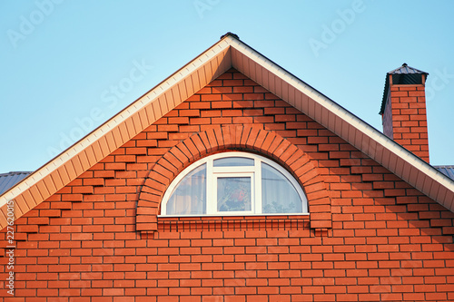 A small window under the roof in a brick cottage