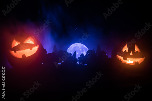 Halloween concept with glowing pumpkins. Strange silhouette in a dark spooky forest at night, mystical landscape surreal lights with creepy man