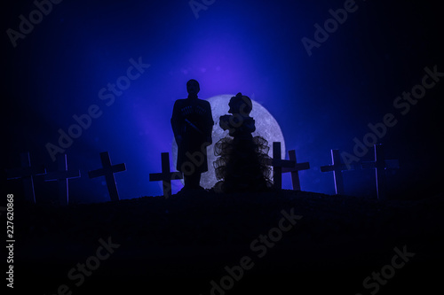 Halloween. Scary zombie bride on a night cemetery holds a pumpkin lantern.