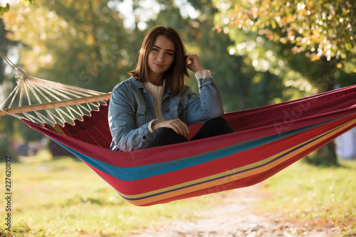Woman resting sitting in hammock, enjoying autumn day