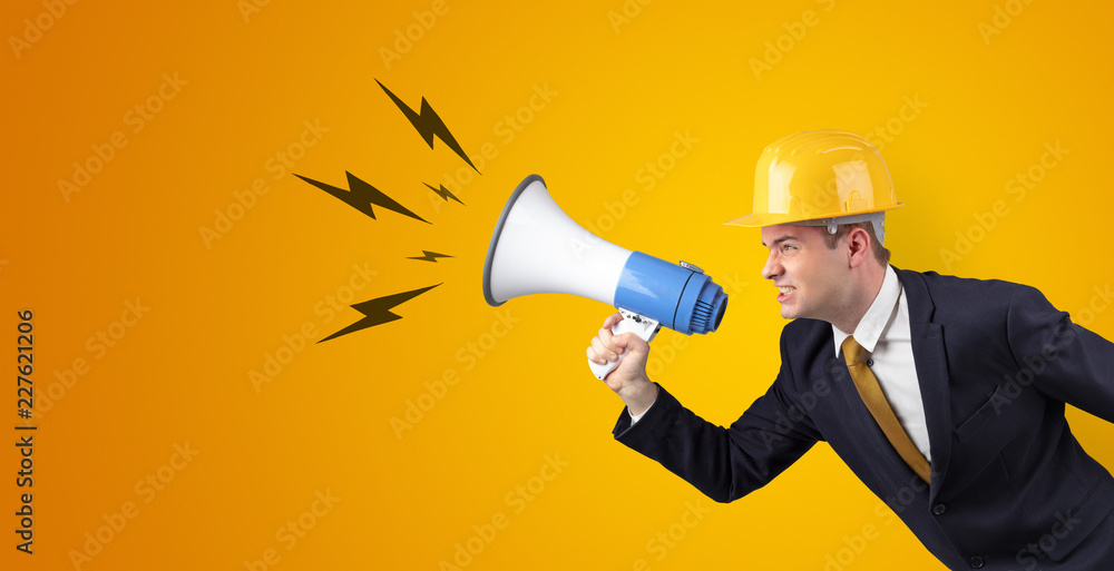 Fototapeta premium Young architect constructor yelling with megaphone and copyspace