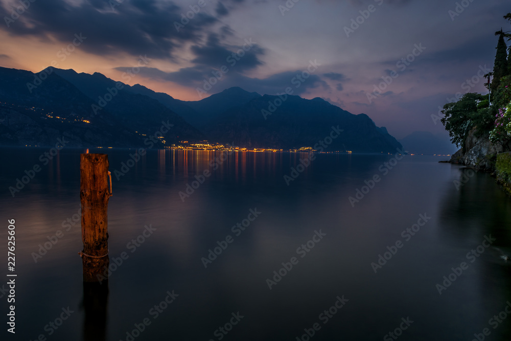Limone and Lake Garda taken from Malcesine at dusk. The lights of Limone can be seen reflecting in the lake. Lake Garda is one of the popular lakes in the northern area of Italy in Europe.
