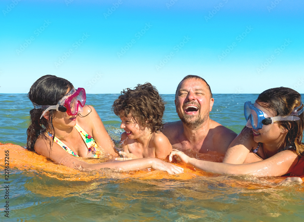happy family with children is swimming and having fun in the sea on an inflatable mattress. happy friendly family concept