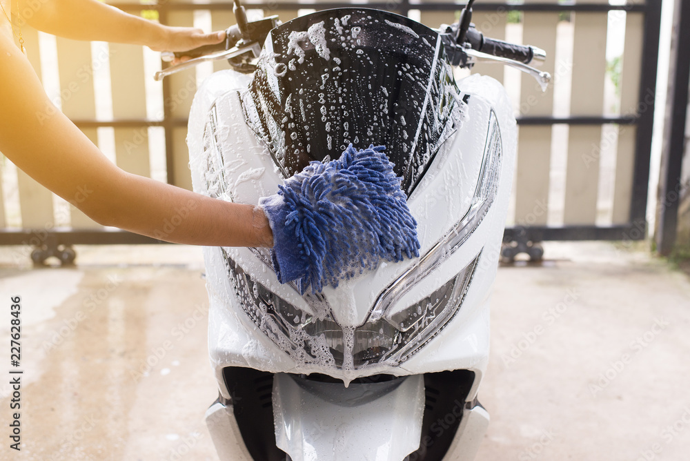 Fototapeta premium Myjnia samochodowa, Szczęśliwy człowiek czyszczenia motocykla mycia wody piany w domu