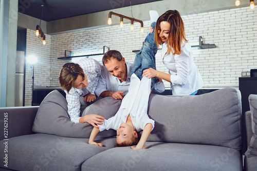 A cheerful family is playing on the couch in the room. © Studio Romantic