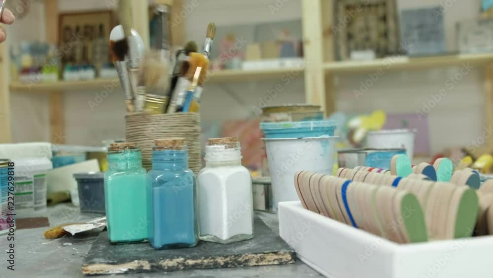 Hands of fingering the jar and bottles of paint, picking the right color in the vases Hands of fingering the jar and bottles of paint, picking the right color in the vases