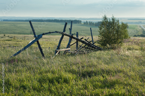 old fallen fence in a summer field
