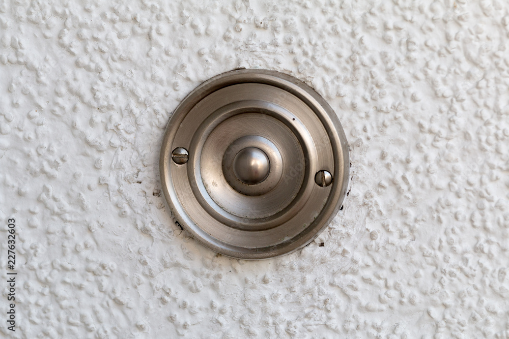 Stainless steel bell button on a white wall Stainless steel bell button on a white wall