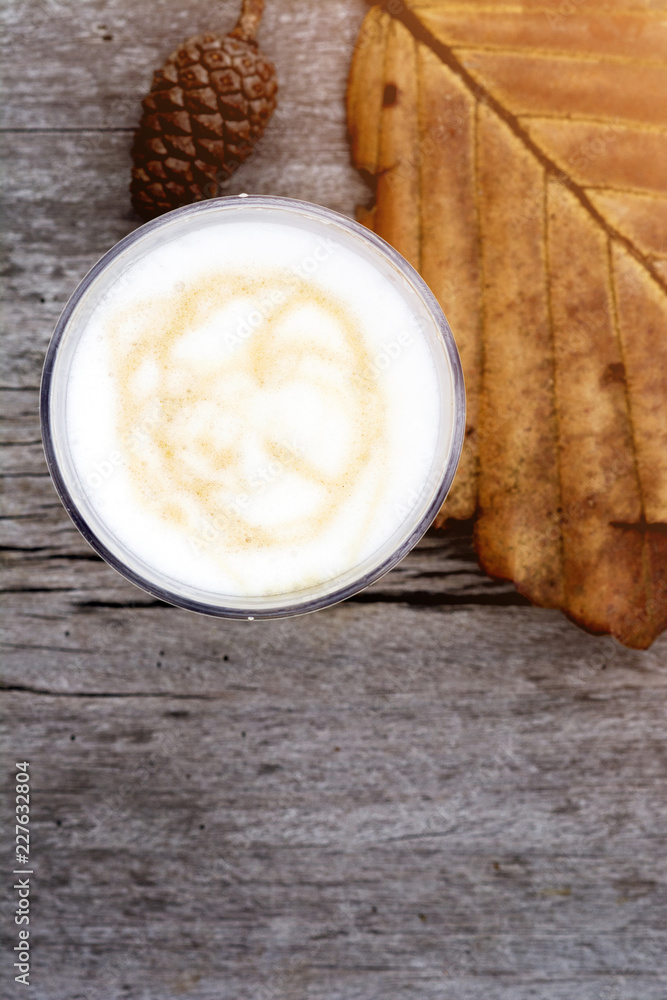 Cup of latte with leaf and pine cone on wooden table, top view image Cup of latte with leaf and pine cone on wooden table, top view image