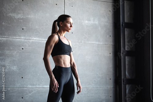 Quadro em tela Sports woman portrait wearing black sportswear on dark wall background