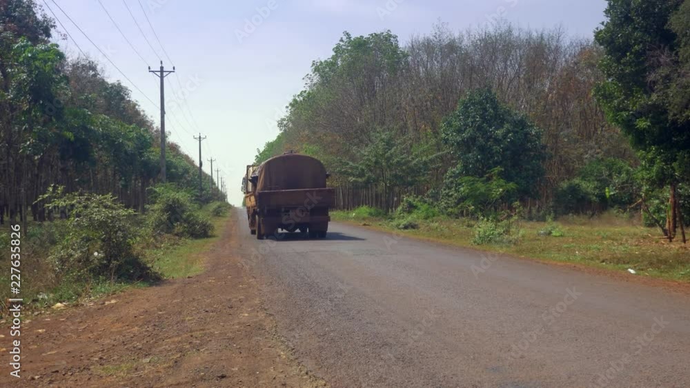 back view of an old small tank truck filled with latex sap through road back view of an old small tank truck filled with latex sap through road