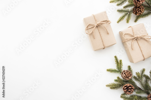 Gift boxes with pine branches and pine cones are on top of white desk table during Christmas or new year. Top view with copy space, flat lay. © satapatms