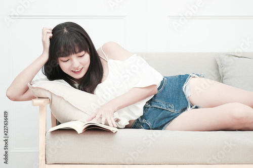 Young woman reading book at home with happy smiley face and relaxation posture, lay in warm and cozy house. However, maybe it's bad posture.