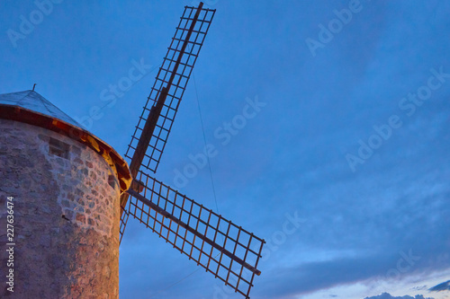 Beautiful close-up of an illuminated windmill sideways at sunset with cloudy sky in Las Ventas with Peña Aguilera, Toledo, Castilla La Mancha, Spain