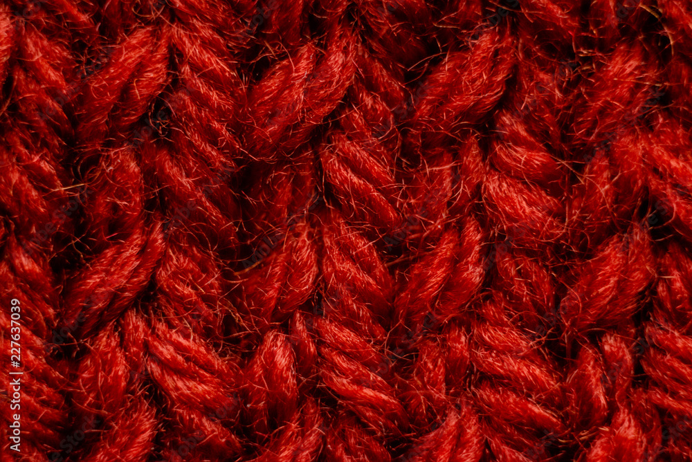 Fototapeta premium Bright red scarf with knitting needles. On green background. Macro pictures.