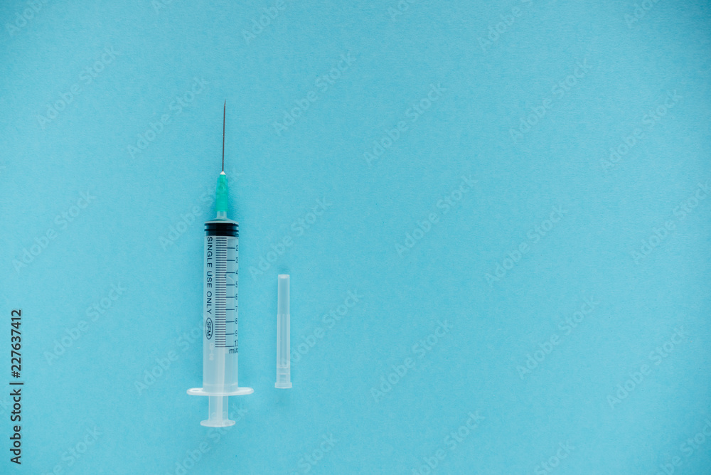 Transparent syringe with a needle, on a background. No liquid in the syringe. Single use only