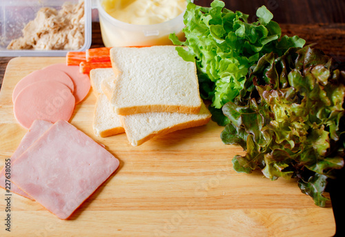 Components of making sandwiches Put on a wooden cutting board with vegetables, crabs, ham, bologna, bread