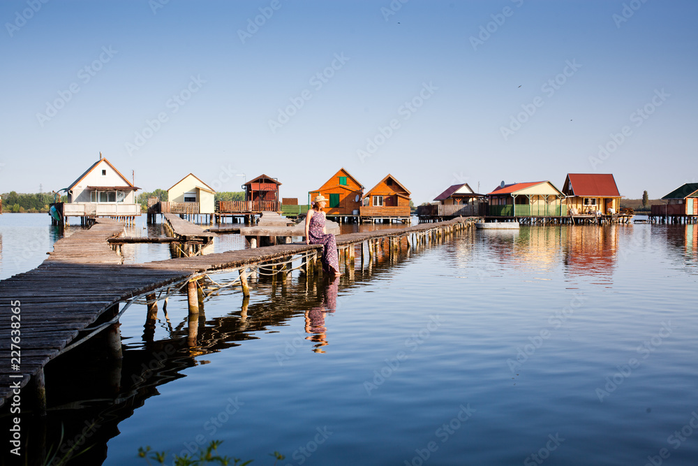 woman walking on the planks at floating village on lake Bokod, Hungary woman walking on the planks at floating village on lake Bokod, Hungary