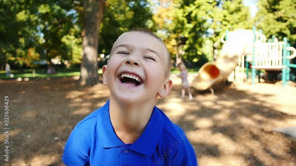 Happy little boy on playground throws his head back and laughs in slow motion Stock ビデオ Adobe