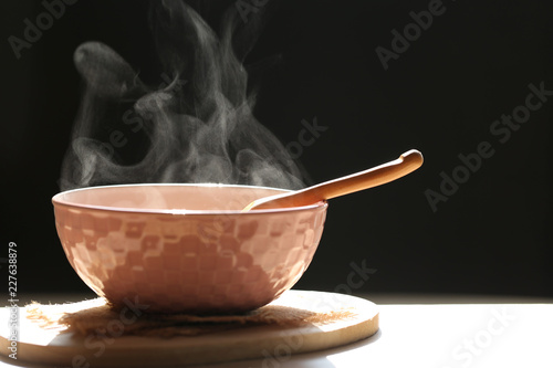 Selective focus of smoke rising with hot soup of instant noodles in cup and spoon on dark background
