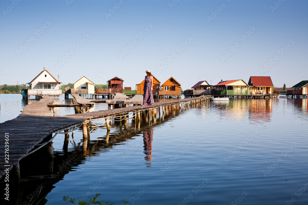 woman walking on the planks at floating village on lake Bokod, Hungary