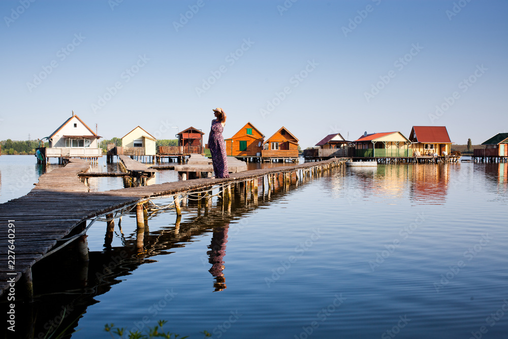 woman walking on the planks at floating village on lake Bokod, Hungary