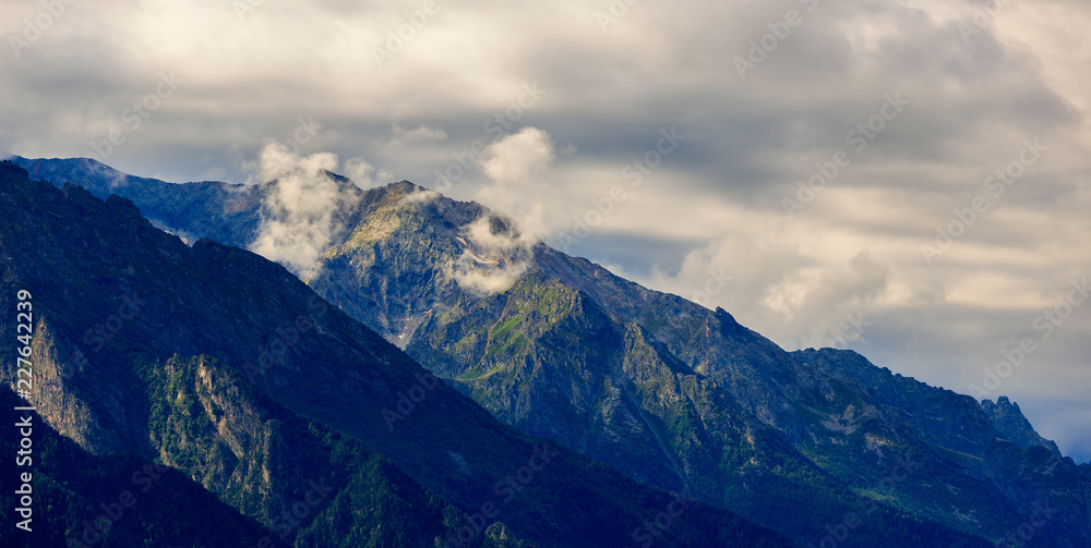 Clouds over the tops of the rocky mountains. Photographed in the Caucasus, Russia.
