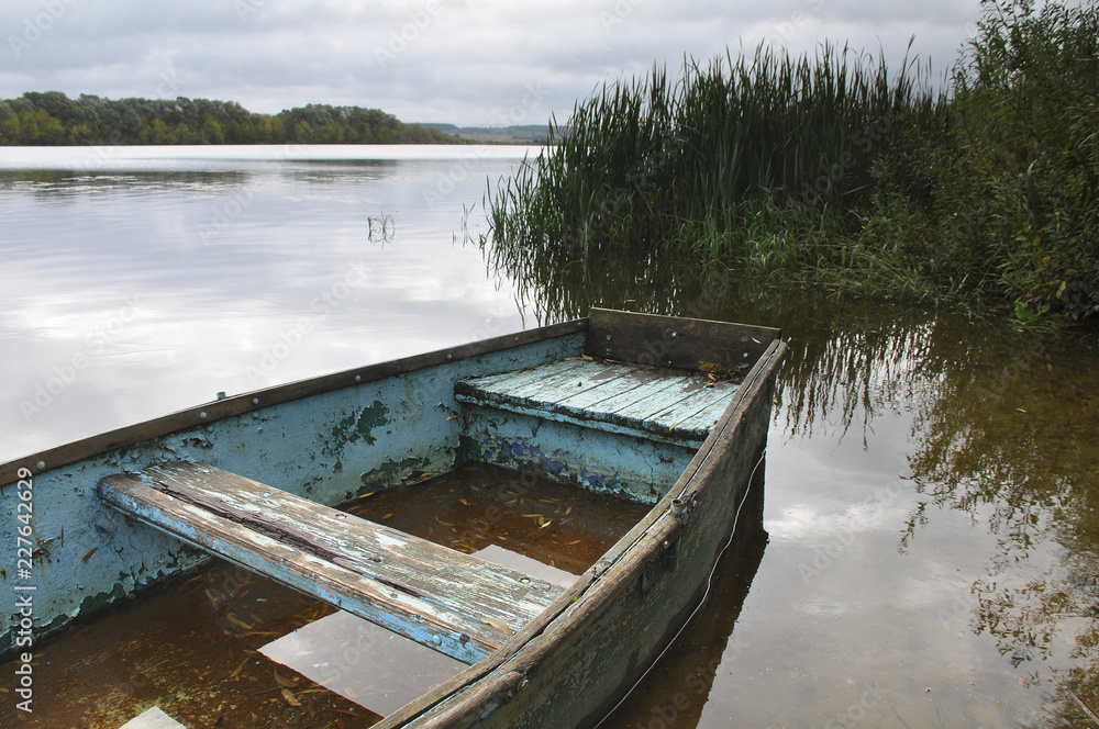 Old boat on water tied to shore 