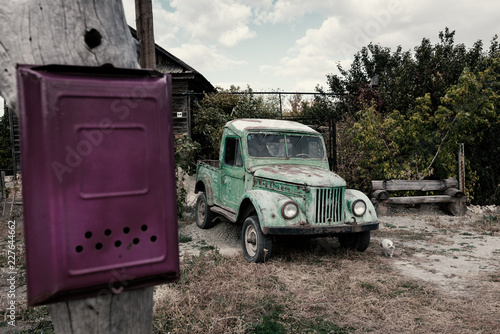 Old car near the house and mailbox on the post