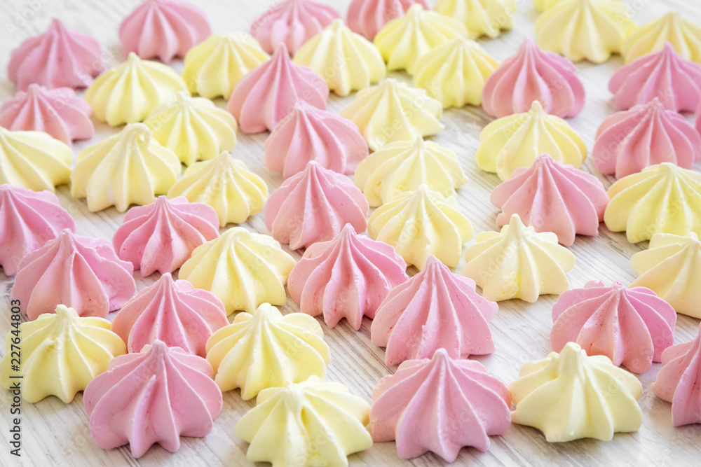 Mini meringues on a white wooden surface, side view. Selective focus. Closeup. Mini meringues on a white wooden surface, side view. Selective focus. Closeup.