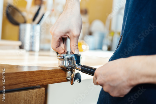 Barista hands holding portafilter and coffee tamper making an espresso coffee.