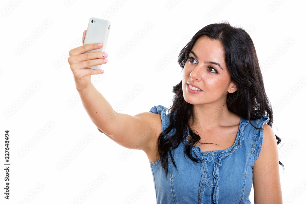 Studio shot of young happy Spanish woman smiling while taking se Studio shot of young happy Spanish woman smiling while taking se