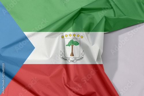 Equatorial Guinea fabric flag crepe and crease with white space, tricolor of green, white and red with a blue triangle and the National Coat of arms.