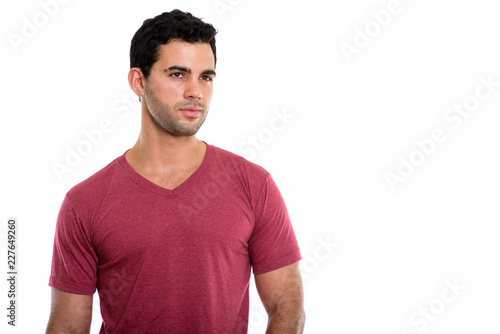 Studio shot of young handsome Hispanic man thinking while lookin