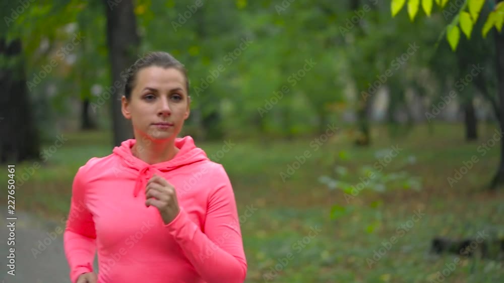 Close up of woman running through an autumn park at sunset Close up of woman running through an autumn park at sunset