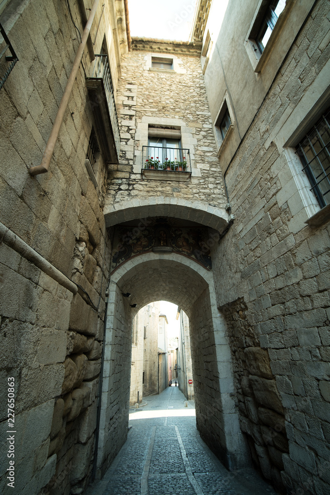 Narrow medieval street with arch in Girona city, Spain